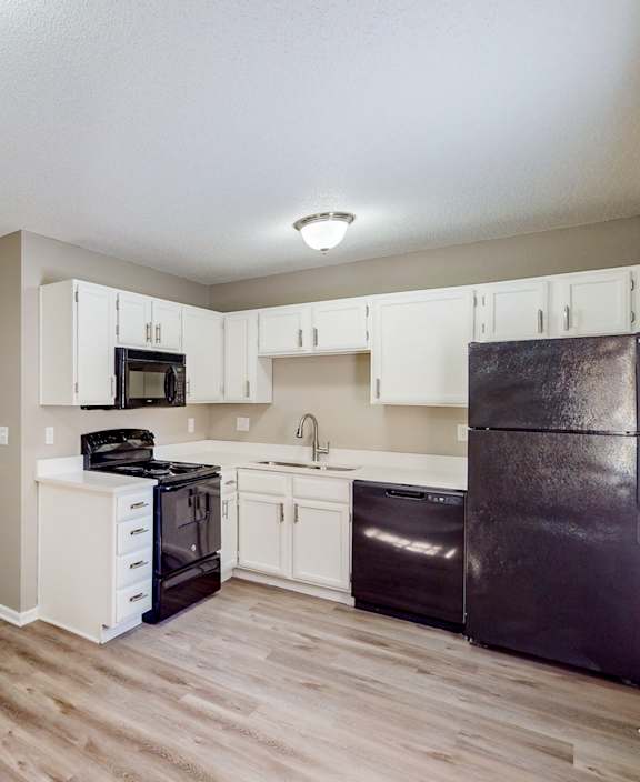 an empty kitchen with white cabinets and a black refrigerator