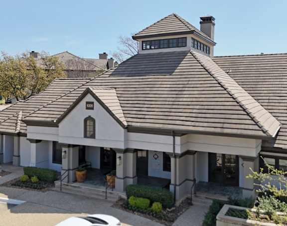 A leasing office with a brown roof and well-trimmed vegetation at Jefferson Place Apartments in Irving, TX