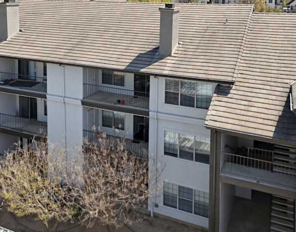Apartment building with brown shingled roofs and white walls.