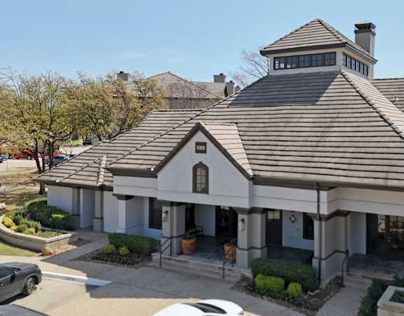 A leasing office with a brown roof and well-trimmed vegetation at Jefferson Place Apartments in Irving, TX