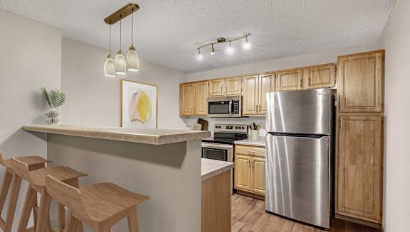 A kitchen with wooden cabinets and a stainless steel refrigerator.