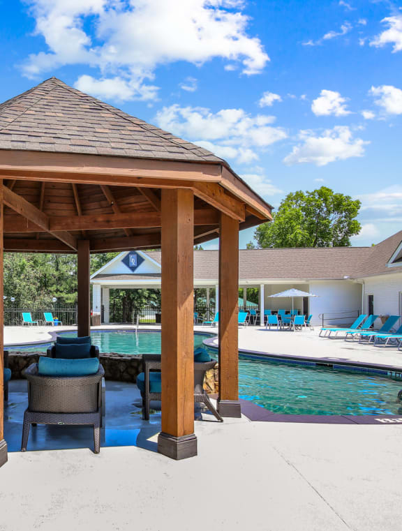 a gazebo with a table and chairs next to a pool at Columbus Apartments in Columbus, Georgia, GA