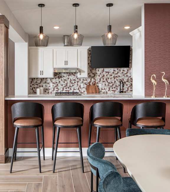 A modern kitchen with a bar area and a dining table.at The Edison at Maple Grove, Minnesota, 55311