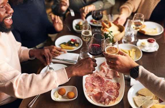 A group of people toasting with wine glasses at a dinner table.