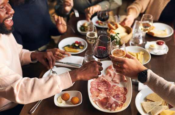 A group of people toasting with wine glasses at a dinner table.