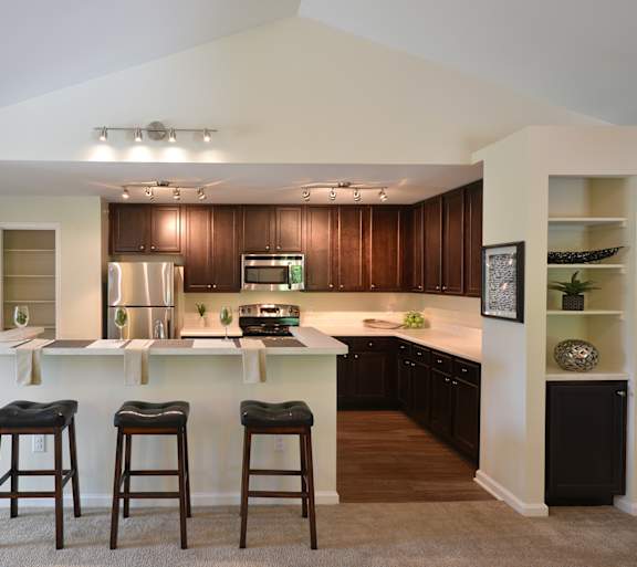 A kitchen with a white island and bar stools.