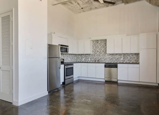 a kitchen with white cabinets and a stainless steel refrigerator