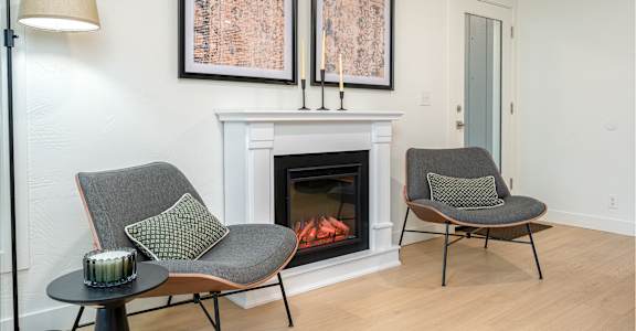 Two chairs are placed in front of a fireplace.