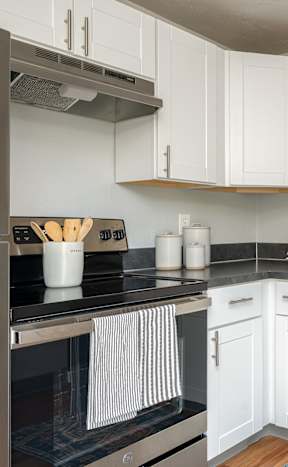 an empty kitchen with stainless steel appliances and white cabinets