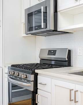 A modern kitchen with a black stove top oven and white cabinets.