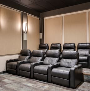 a room with a row of leather chairs and a projector screen