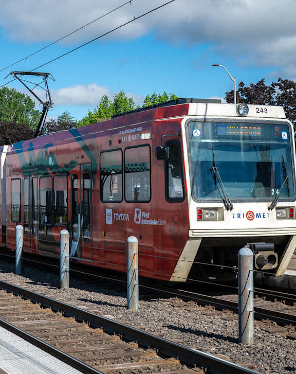 A red and white train is on the tracks with the number 24b on the front.