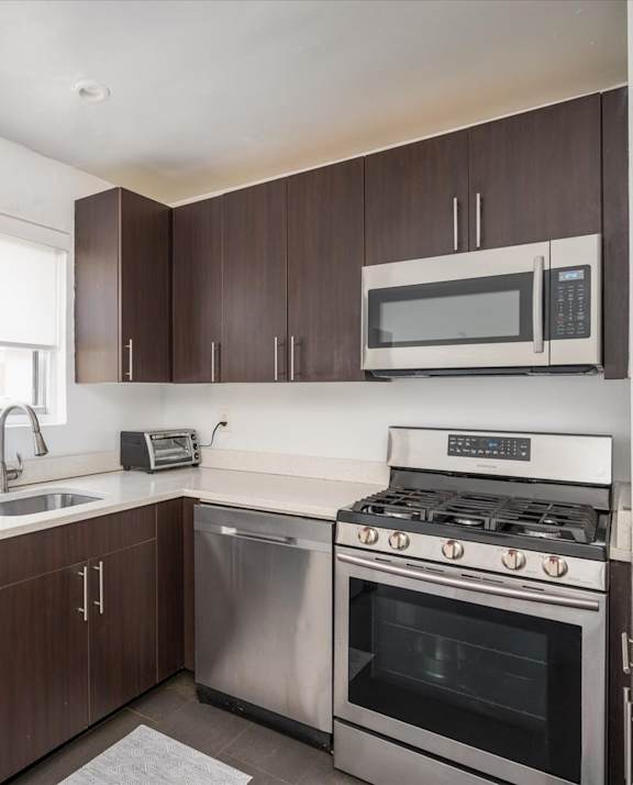 A modern kitchen with a stainless steel refrigerator, microwave, and oven.