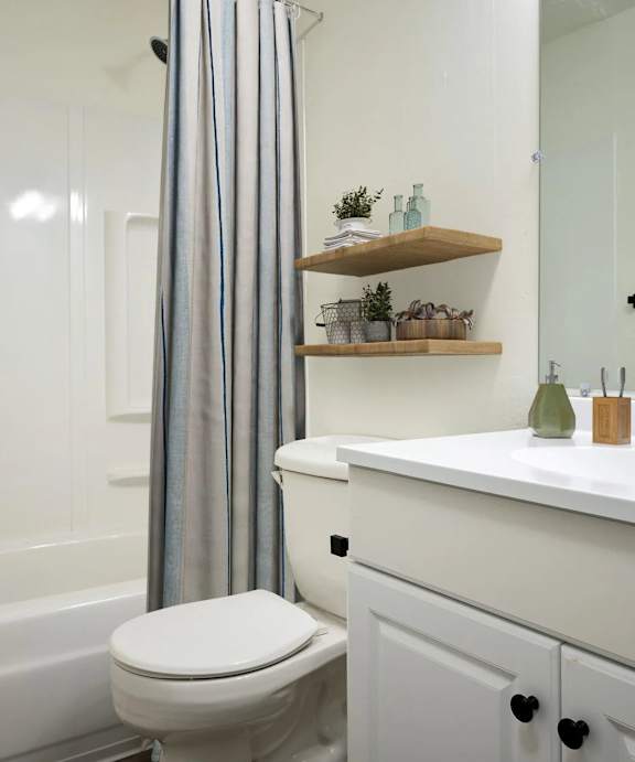 A white bathroom with a toilet, sink, and a shower curtain.
