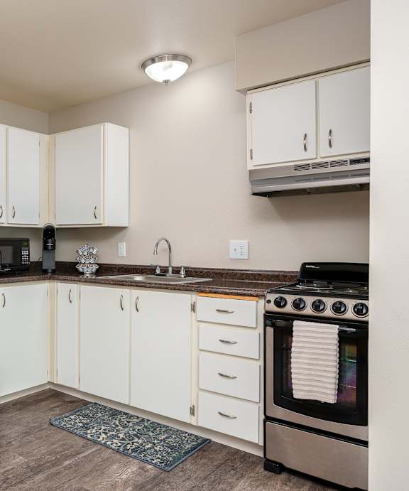 A kitchen with white cabinets and a stainless steel refrigerator.