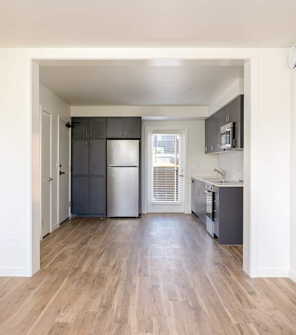 A kitchen with a refrigerator, microwave, and oven.