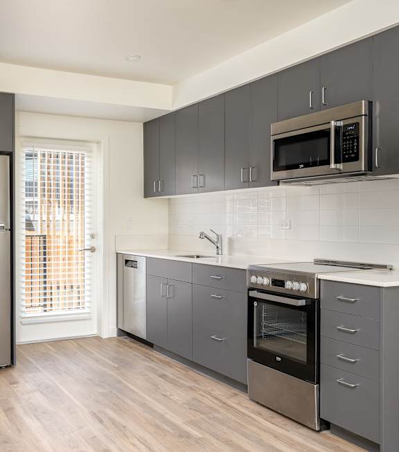A modern kitchen with a refrigerator, oven, and microwave.