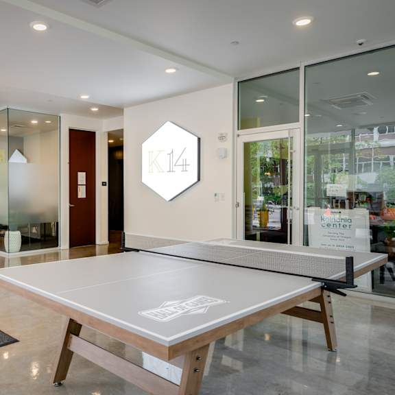 A ping pong table is in the middle of a room with a glass wall.