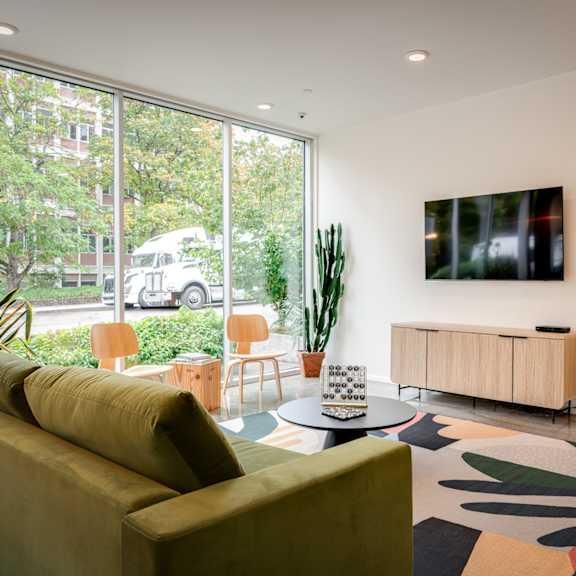 A living room with a green couch and a large window.