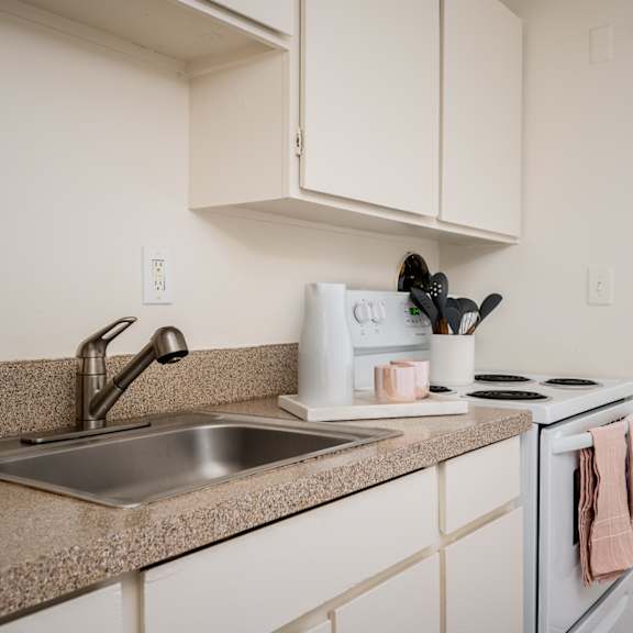 A kitchen with a sink, stove, and cabinets.