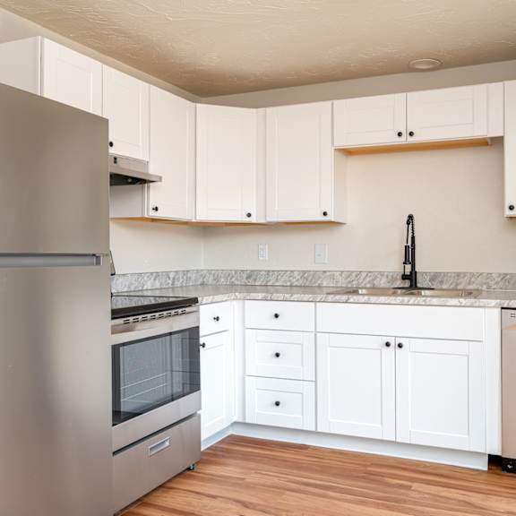 A modern kitchen with white cabinets and a stainless steel refrigerator.