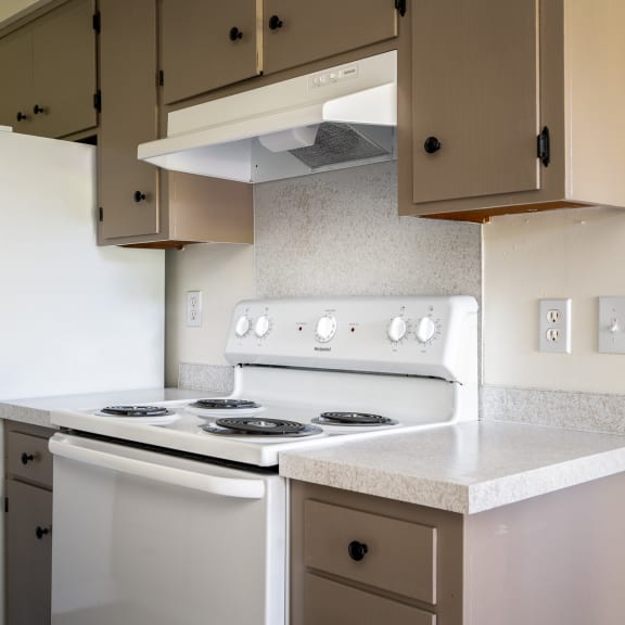 an empty kitchen with white appliances and a refrigerator