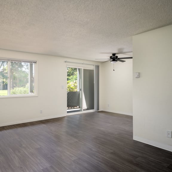 an empty living room with a window and a ceiling fan