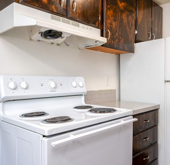 A white stove and refrigerator in a kitchen with white cabinets.