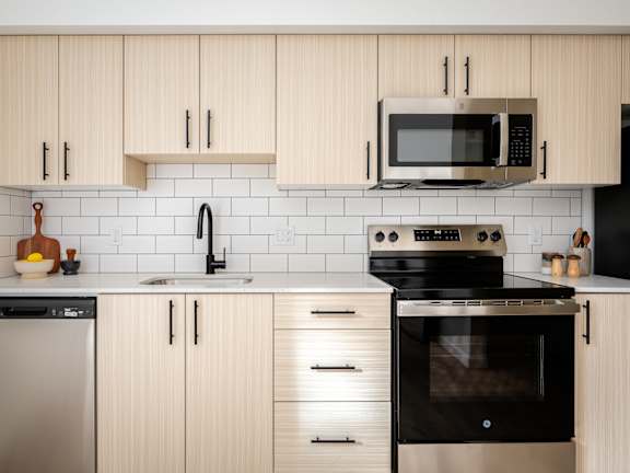 A modern kitchen with wooden cabinets and black appliances.