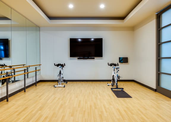a spacious fitness room with cardio equipment and windows