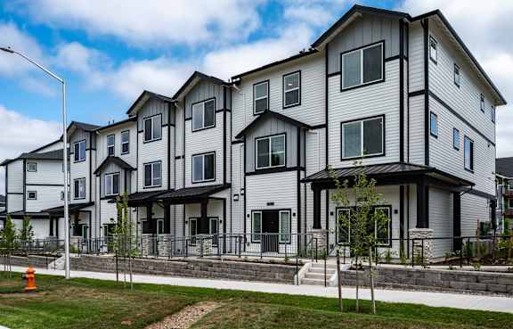 Three-Bedroom Apartments in Oregon City, OR - Timberview - Exterior View of Apartment Building with Concrete Walkway, Trimmed Trees, and Manicured Grass.