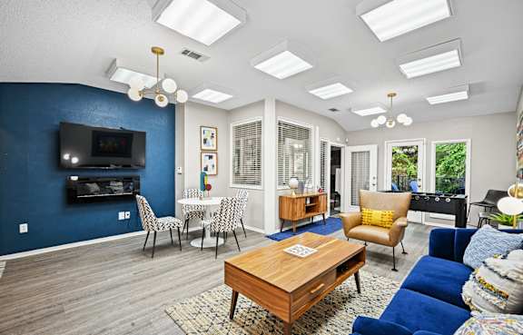 a living room with a couch coffee table and chairs and a television on the wall