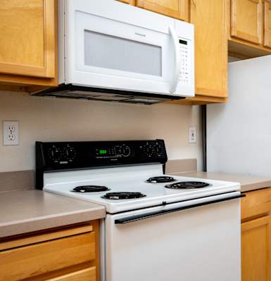 A white microwave oven is mounted above a black stove in a kitchen.