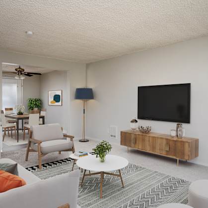A living room with a white couch, a coffee table, and a television.