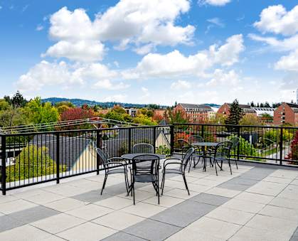 the terrace of a balcony with tables and chairs and a view of the city