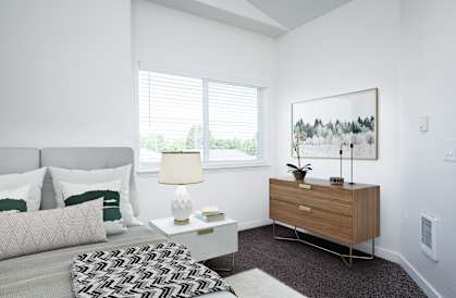 a bedroom with a bed and a dresser with a lamp and a painting on the wall