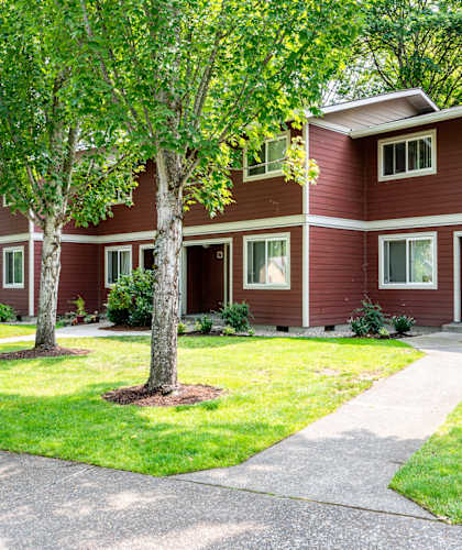 A red house with a white roof and a tree in front.