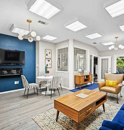 a living room with a couch coffee table and chairs and a television on the wall