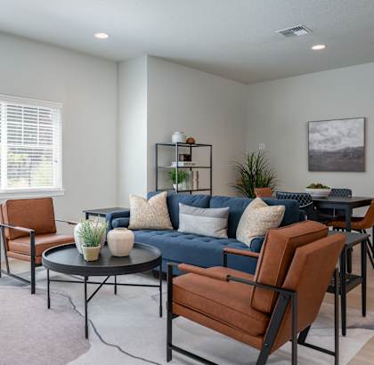 a living room with a blue couch and brown chairs