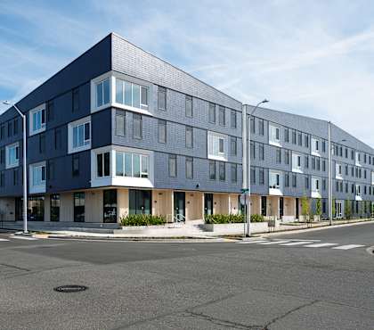 A modern multi-story building with a flat roof and large windows.