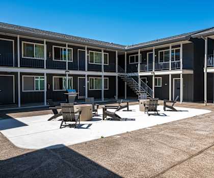 a courtyard with tables and chairs in front of a building