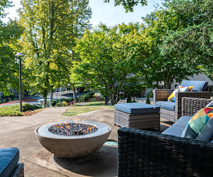 A patio with a fire pit and wicker furniture.