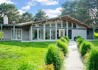 A modern house with a glass door and a wooden roof.