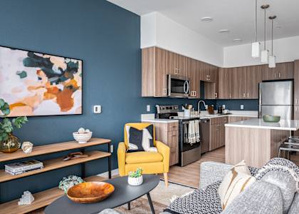 a living room and kitchen with a blue wall and a yellow chair and a table