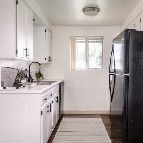 a kitchen with white cabinets and a black refrigerator