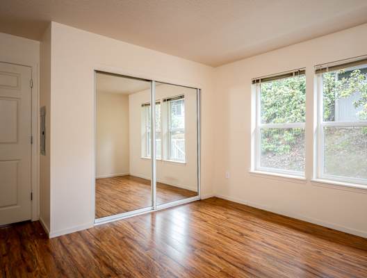 A room with a sliding glass door and wooden floors.