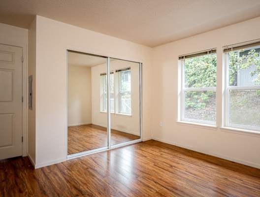 A room with a sliding glass door and wooden floors.
