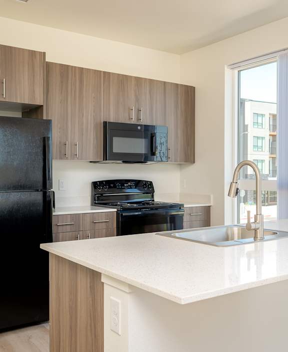 A black refrigerator is in a kitchen with a white counter.