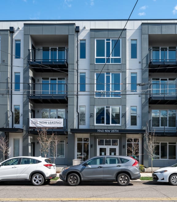 an image of an apartment building with cars parked in front of it