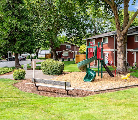 A playground with a green slide and a yellow duck in the foreground.